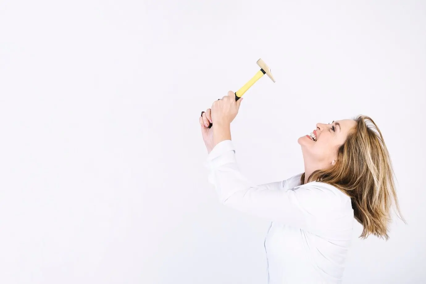 Erwachsene Frau, die Schwierigkeiten mit einem Hammer hat.